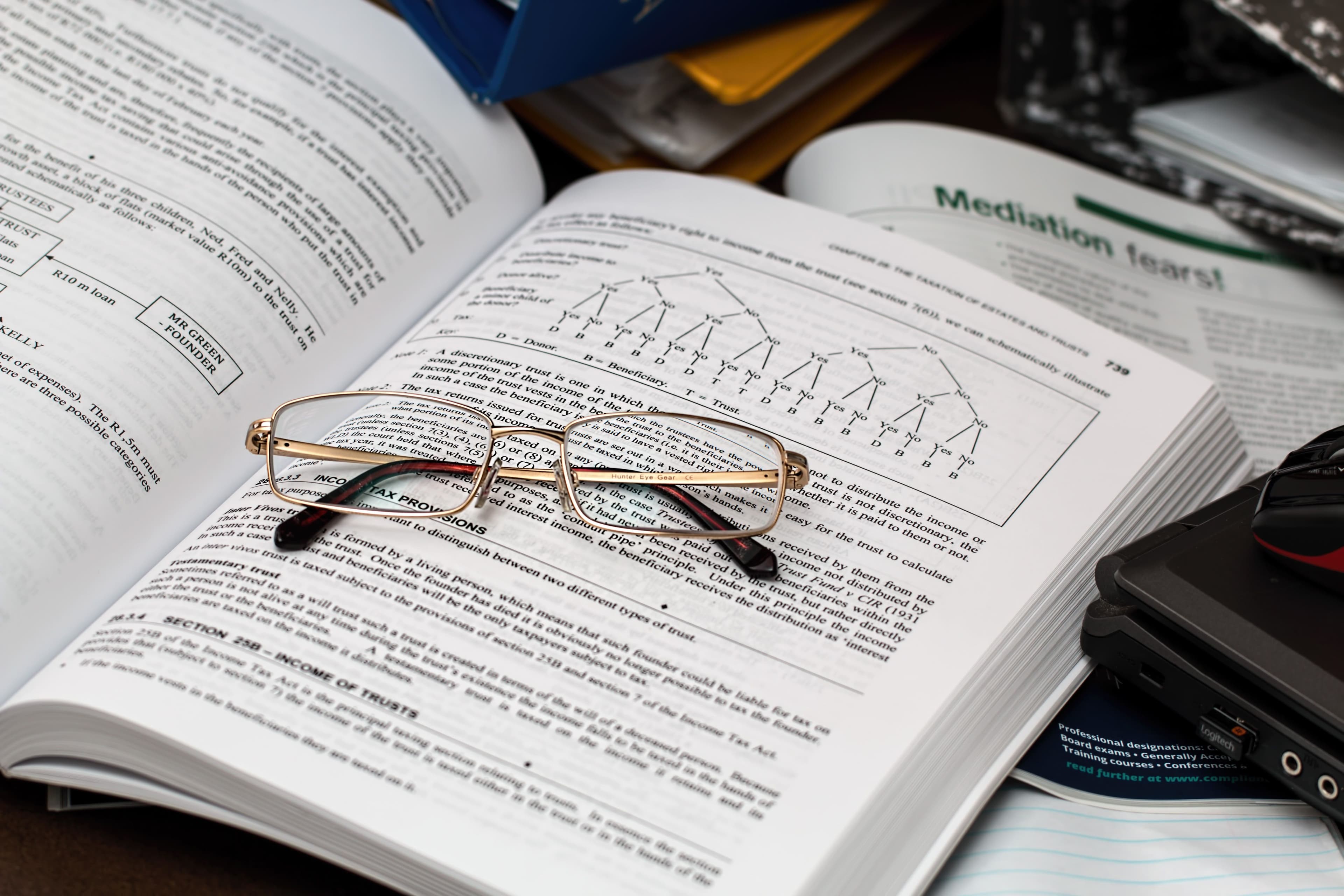 A pair of glasses rests on an open textbook filled with complex diagrams and text